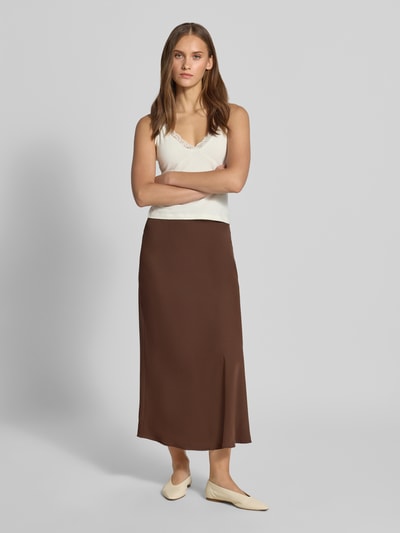 Frauenmodel trägt Ausgestellter Maxi-Rock mit elastischem Bund Modell 'FRANAN' von PIECES in Braun, kombiniert mit weißem Top, Ganzkörperansicht von vorne. Damen Maxi-Rock von PIECES.