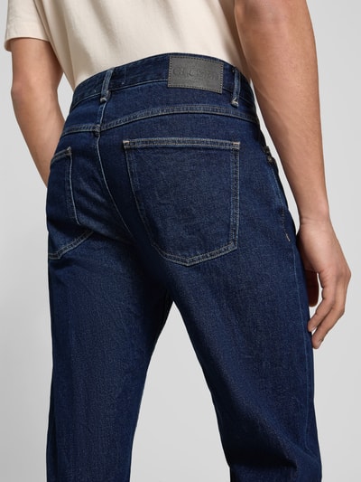 Männermodel trägt Straight Fit Jeans mit Logo-Patch von Closed aus elastischem Baumwoll-Mix, 5-Pocket-Design, Rückansicht Nahaufnahme.