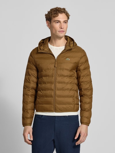 Männermodel trägt braune Regular Fit Bomberjacke mit Ecodown-Füllung von Lacoste, Herren Bomberjacke, Ganzkörperansicht von vorne.