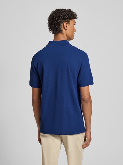 Männermodel trägt Regular Fit Poloshirt aus reiner Baumwolle Modell 'PALLAS' von BOSS in Blau, Struktur Piqué, Ganzkörperansicht Rückansicht.