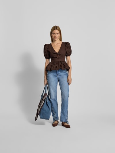Frauenmodel trägt Blusenshirt mit V-Ausschnitt von ROTATE, Reine Baumwolle, Lockerer-Schnitt, Schleifen-Detail, braun, Ganzkörperansicht von vorne.
