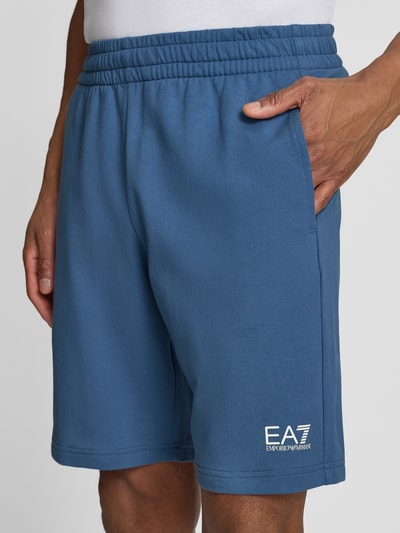 Männermodel trägt Sweatshorts mit Logo und Eingrifftaschen von EA7 Emporio Armani aus reiner Baumwolle, Regular-Fit, Nahaufnahme Oberschenkel.