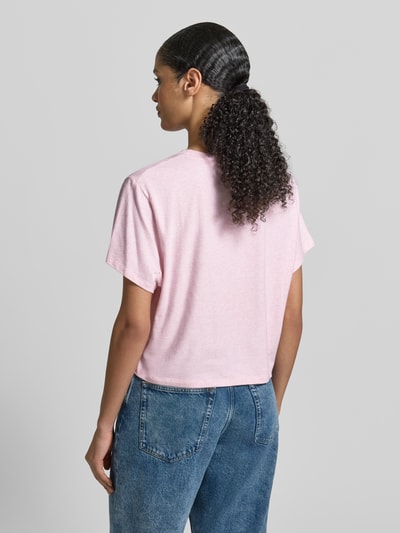 Frauenmodel trägt T-Shirt mit geripptem Rundhalsausschnitt von American Vintage, lockerer Schnitt, hellrosa, glatte Textur, Rückansicht, Ganzkörperansicht.