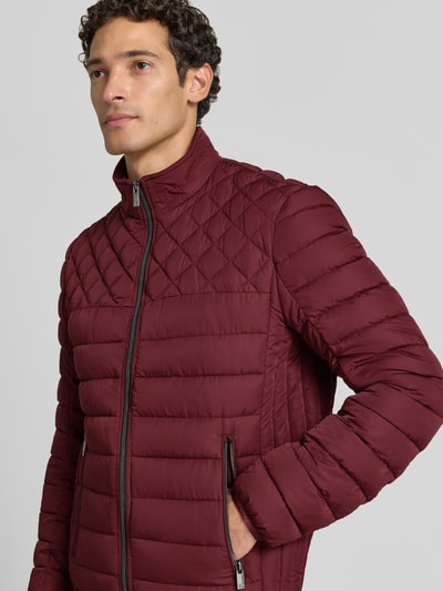 Männermodel trägt Steppjacke mit Stehkragen und Reißverschlusstaschen von Christian Berg Men in Dunkelrot, Regular Fit, Nahaufnahme Oberkörper.