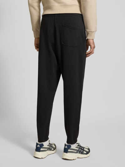 Männermodel trägt Regular Fit Sweatpants aus Baumwoll-Mix von Tommy Jeans, Optik: unifarben, Materialverarbeitung: Sweat, Ganzkörperansicht Rückansicht.