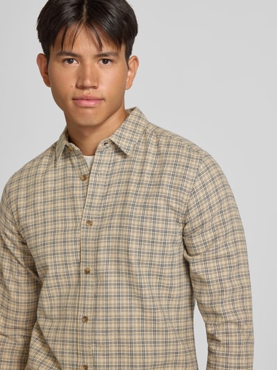 Männermodel trägt Slim Fit Freizeithemd aus reiner Baumwolle Modell 'GUDMUND' von ONLY & SONS in beigem Karo-Muster, Nahaufnahme Oberkörper.