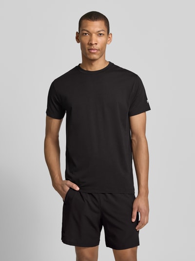 Mężczyzna model nosi Regular Fit T-Shirt mit Logo-Print von Fabletics, czarny, elastyczna bawełna, krój regular fit, logo, okrągły dekolt, długość tyłu w rozmiarze M: 65 cm, zdjęcie całej sylwetki z przodu.