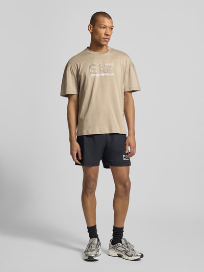 Mannelijk model draagt T-shirt met Logo en ronde hals van EA7 Emporio Armani, puur katoen, regular fit, ruglengte maat M 68 cm, geheel vooraanzicht.