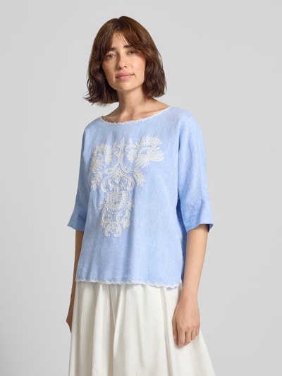 Modelka nosi Blusenshirt mit Leinen-Anteil und Motiv-Stitching von Christian Berg Woman, Mieszanka wiskozy i lnu, krój loose fit, dekolt w łódkę z kontrastową lamówką, wyhaftowany motyw, jasnoniebieski odcień, Długość tyłu w rozmiarze 36: 55 cm, Długość rękawów w rozmiarze 36: 34 cm, całkowity widok z przodu.
