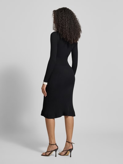 Vrouwenmodel draagt Slim Fit tricotjurk uit viscosemix Model 'Laurel' van Guess, zwart, lang, met opgestikte zakken, ruglengte 110 cm, volledig lichaam achteraanzicht.