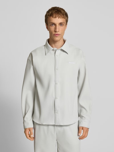 Männermodel trägt Regular Fit Freizeithemd mit Kentkragen und Label-Stitching von Pegador, hellgrau mit feiner Streifenstruktur, Ganzkörperansicht von vorne, Material-Mix mit Stretch-Anteil.