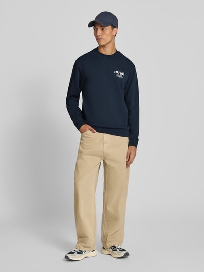 Männermodel trägt Regular Fit Sweatshirt aus reine katoen model 'Nespon' van HUGO, donkerblauw, zandkleurige broek, Heren sweatshirt, Ganzkörperansicht von vorne