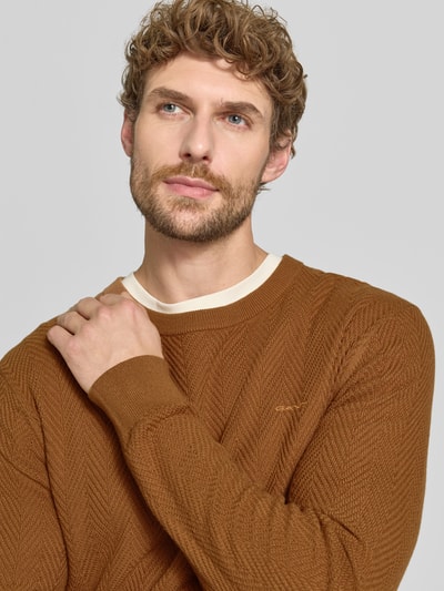 Männermodel trägt Regular Fit Pullover aus Baumwoll-Woll-Mix von GANT in warmem Braun mit feiner Struktur, Nahaufnahme Oberkörper.