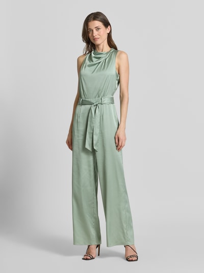 Frauenmodel trägt Jumpsuit aus Satin im ärmellosen Design von comma in zartem Mintgrün mit Stoffband und weitem Bein, Ganzkörperansicht von vorne. Taillierte Passform, Nahtreißverschluss, Rückenlänge 35 cm, Brustweite 45 cm, Gesamtlänge 110 cm, Innenbeinlänge 80 cm.
