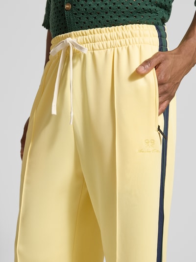Männermodel trägt Trackpants mit Galonstreifen von ANOTHER COTTON LAB in Gelb, elastischer Bund, Relaxed Fit, Nahaufnahme Oberkörper.