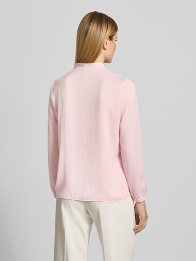 Kobiece model nosi Regular Fit Bluse mit V-Ausschnitt von Marc Cain, jasnoróżowa, detal z logo, długość tyłu 65 cm, długość rękawów 59 cm, krój regular fit, widok całej sylwetki z tyłu.