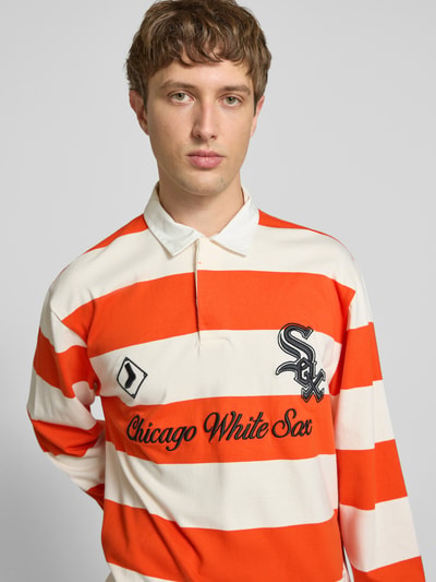 Männermodel trägt Relaxed Fit Poloshirt aus reiner Baumwolle von Champion, orange-weiß gestreift, Statement-Stitching, Nahaufnahme Oberkörper.