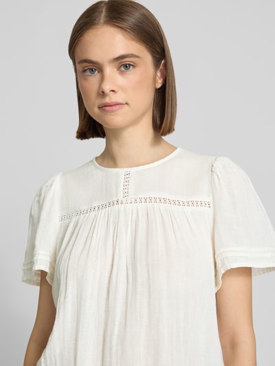 Vrouwenmodel draagt Relaxed Fit Bluse uit pure katoen model 'SIKKA' van Pieces in effen wit met korte mouwen, tuniekkraag en ronde hals, mousseline structuur, 1-knoopsluiting, plooidetails, bovenlichaam close-up vooraanzicht.