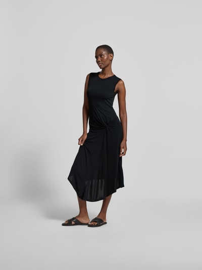 Frauenmodel trägt Slim Fit Midikleid aus reiner Viskose von Joseph, Raffungen, asymmetrisches Design, ärmellos, Unifarbe schwarz, Ganzkörperansicht von vorne.
