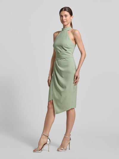 Modelka nosi Slim Fit Kleid mit Stehkragen od Lipsy, elastyczna mieszanka materiałów, asymetryczny krój, bez rękawów, marszczenia, długość tyłu w rozmiarze 36: 105 cm, szerokość w rozmiarze 36: 34 cm, jasna zieleń, gładka tekstura, pełen widok z przodu.