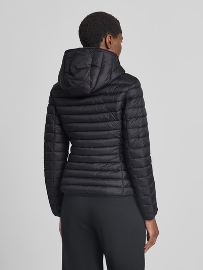 Frauenmodel trägt schwarze Steppjacke mit Zweiwege-Reißverschluss Modell 'DAISY' von Save The Duck, Rückenansicht, Ganzkörperansicht Rückansicht. Damen Steppjacke im Slim Fit mit Kapuze, Reißverschlusstaschen, Größe S: Rückenlänge 57 cm, Schulterbreite 44 cm, Brustweite 48 cm, Ärmellänge 60 cm.