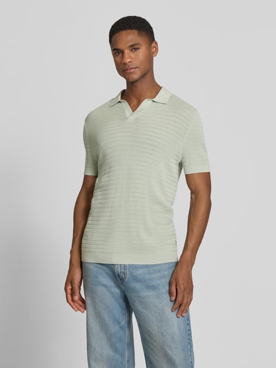 Männermodel trägt Slim Fit Strick-Poloshirt mit Strukturmuster Modell 'BRAIAN' von Drykorn in Hellgrün, reine Baumwolle, V-Ausschnitt, Ganzkörperansicht von vorne.