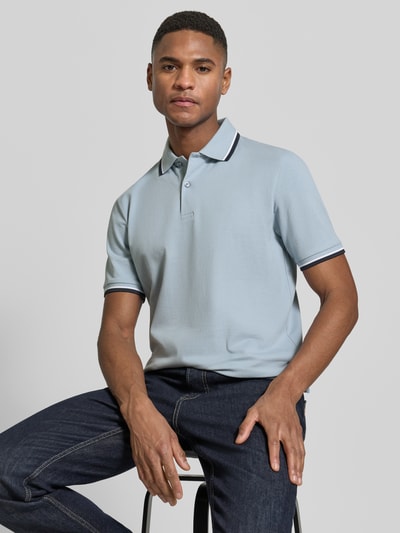 Männermodel trägt Slim Fit Poloshirt aus Bio-Baumwoll-Mix Modell 'SLIM ATLAS SPORT' von SELECTED HOMME, unifarben, Kurzarm, Kontraststreifen, Piqué-Textur, Ganzkörperansicht von vorne.