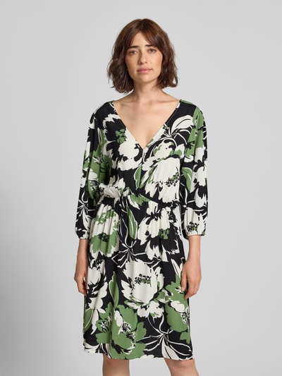 Frauenmodel trägt Knielanges Kleid aus Viskose im Allover-Look Modell 'Fe44li' von ZABAIONE in A-Linie, V-Ausschnitt, 3/4-Arm, florales Muster in Schwarz, Grün und Weiß, Ganzkörperansicht von vorne.