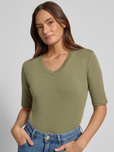 Frauenmodel trägt T-Shirt mit V-Ausschnitt von Christian Berg Woman, olivgrün, Regular Fit, Baumwoll-Elasthan-Mix, Nahaufnahme Oberkörper.