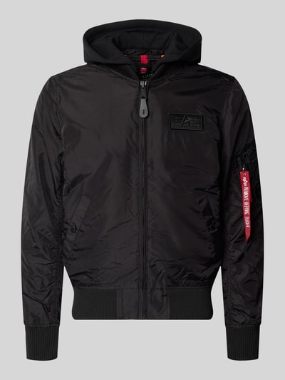Produktfoto, schwarzer Blouson mit Logo-Anhänger Modell 'MA-1 TT' von Alpha Industries, Kapuze aus Sweat, elastische Abschlüsse, Armtasche, Reißverschluss