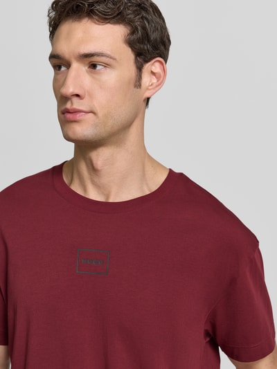 Männermodel trägt Relaxed Fit T-Shirt aus Baumwoll-Mix Modell 'LAZE' von HUGO in Unifarben mit Label-Print, Nahaufnahme Oberkörper.