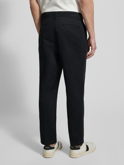 Męski model nosi Regular Fit Chino aus Baumwoll-Mix Modell 'TAAMIR PLEATED' von Armedangels, jednokolorowy, mieszanka bawełny, krój regular fit, wyhaftowane logo, szlufki na pasek, zapięcie na haftkę i ukryty zamek błyskawiczny, kieszenie z tyłu i wpuszczane boczne, Ganzkörperansicht Rückansicht.