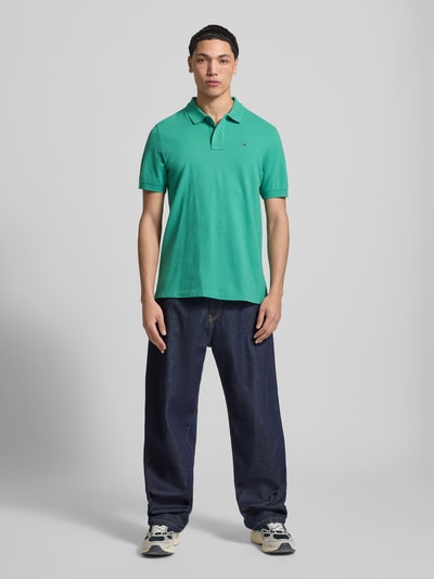 Mannenmodel draagt Regular Fit Poloshirt uit puur katoen van Tommy Jeans, look: effen, piqué, logostitching, polokraag, korte mouw, rompzoom met split. Vooraanzicht volledige lichaamsopname.