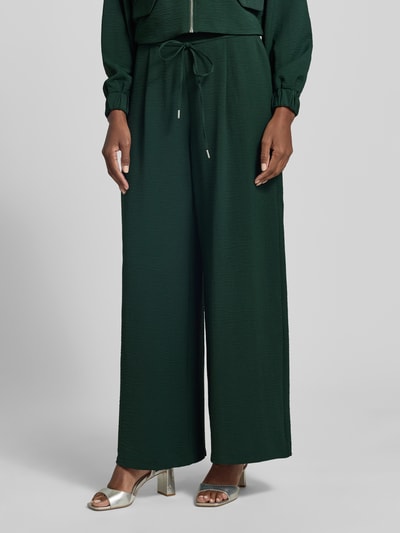 Frauenmodel trägt Hose mit elastischem Bund und Bindegürtel von Zero, dunkelgrün, Strukturmuster, Relaxed Fit, Nahaufnahme Unterkörper.