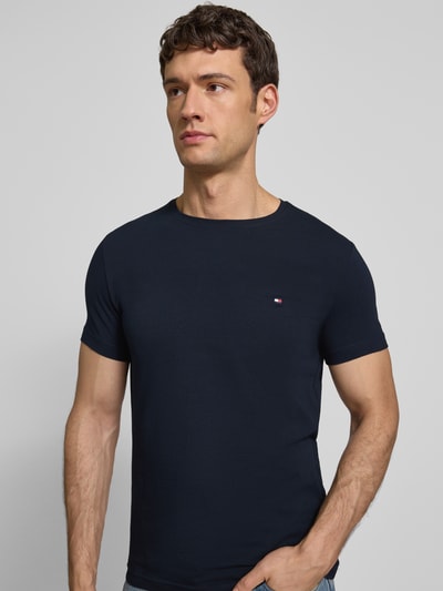 Männermodel trägt Slim Fit T-Shirt mit Rundhalsausschnitt von Tommy Hilfiger aus Baumwoll-Elasthan-Mix mit Logo-Stickerei, Nahaufnahme Oberkörper.