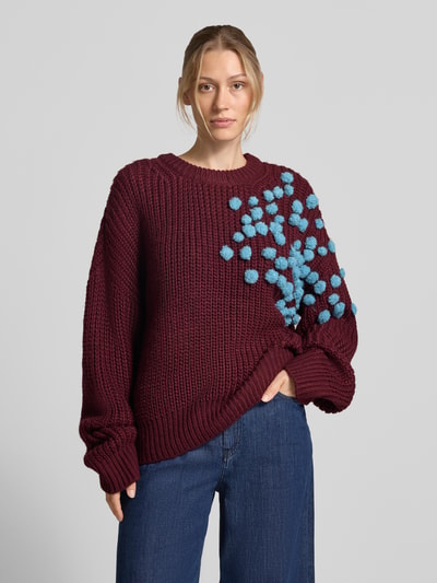Frauenmodel trägt Relaxed Fit Pullover mit Woll-Anteil Modell 'KOSTAR' von Essentiel Antwerp in Dunkelrot mit blauen Textur-Details, Nahaufnahme Oberkörper. Damen Pullover von Essentiel Antwerp.
