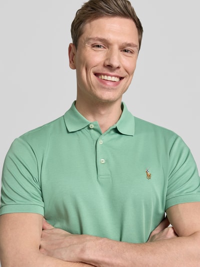 Männermodel trägt Regular Fit Poloshirt aus reine katoen van Polo Ralph Lauren, look: effen, pasvorm: regular fit, gestikt logo, polokraag, 3-knoopsluiting, korte mouw, mouwboord: geribd, rompzoom: met split, materiaalverwerking: jersey, detailopname bovenlichaam.
