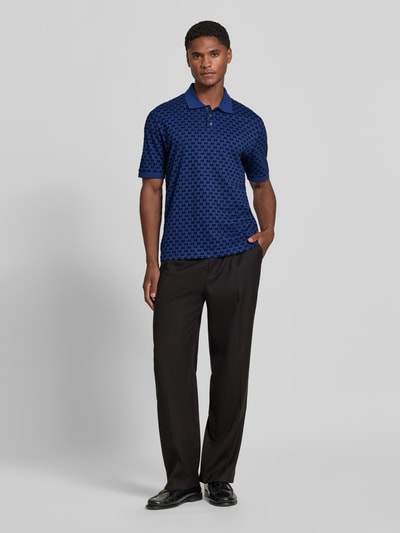 Männermodel trägt Regular Fit Poloshirt aus reiner Baumwolle von Armani Exchange in Blau mit Allover-Logo-Print, Ganzkörperansicht von vorne.