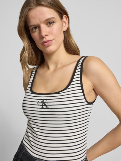 Frauenmodel trägt Trägertop in Ripp-Optik mit Logo von Calvin Klein Jeans, Slim-Fit, Baumwoll-Elasthan-Mix, Rückenlänge 59 cm, Nahaufnahme Oberkörper.