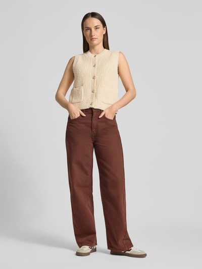 Frauenmodel trägt Strickweste Melange Effekt mit Schmuckknopf von Christian Berg Woman in Beige, kombiniert mit brauner Hose, Baumwoll-Mix, Regular Fit, gerippte Abschlüsse, Rundhalsausschnitt, Eingrifftaschen, Knopfleiste, Ganzkörperansicht von vorne.