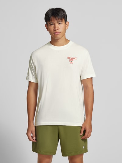 Männermodel trägt Regular Fit T-Shirt aus reiner Baumwolle mit Label-Detail von New Balance in Weiß, Ganzkörperansicht von vorne. Modell 'GRAB A BITE TOKYO', Rückenlänge bei Größe M 70 cm.