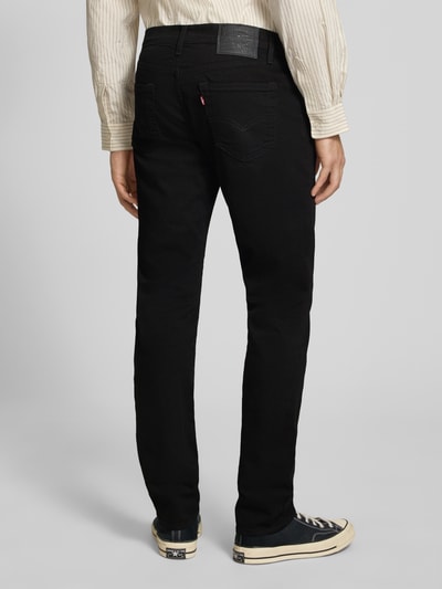 Männermodel trägt Slim Fit Jeans Modell '511®' von Levi's® aus Baumwoll-Mix mit Stretch-Anteil, schwarzer Farbton, 5-Pocket-Design, Label-Detail, Ganzkörperansicht Rückansicht.