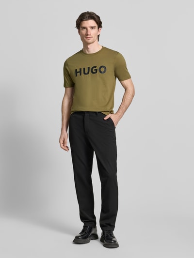 Männermodel trägt Regular Fit T-Shirt aus reiner Baumwolle Modell 'DULIVIO' von HUGO, Optik: Unifarben, Label-Print, Ganzkörperansicht von vorne.