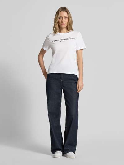 Frauenmodel trägt Regular Fit T-Shirt aus reiner Baumwolle von Tommy Hilfiger, weiß, unifarben, Logo-Detail, Ganzkörperansicht von vorne.