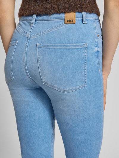 Frauenmodel trägt Slim Fit Jeans aus Baumwoll-Mix Modell 'STATE' von BOSS in Denim-Optik mit Label-Patch und 5-Pocket-Design, Detailaufnahme Rückansicht.