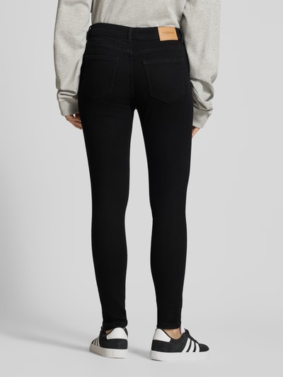 Kobiece model prezentuje Slim Fit Jeans im 5-Pocket-Design od REVIEW, czarny kolor, elastyczna mieszanka bawełny, krój slim fit, 5 kieszeni, zapięcie na guzik i zamek błyskawiczny, szerokość w rozmiarze 27: 34 cm, długość wewnętrzna nogawki w rozmiarze 27: 71 cm, widok całej sylwetki z tyłu.