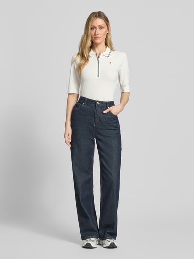 Frauenmodel trägt Slim Fit Poloshirt aus Lyocell-Mix von Tommy Hilfiger, Optik: Unifarben, Logo-Stitching, Kontraststreifen, Passform: Slim-Fit, Verschluss: kurze Knopfleiste, Ärmelform: 1/2-Arm, Materialverarbeitung: Piqué, Ganzkörperansicht von vorne.