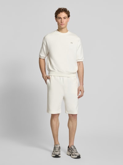 Männermodel trägt Relaxed Fit Sweatshorts aus reiner Baumwolle von Lacoste, unifarben, elastischer Bund, seitliche und Gesäßtaschen, Ganzkörperansicht von vorne
