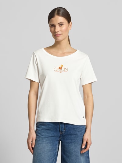 Frauenmodel trägt T-Shirt mit Motiv-Print und Strasssteinbesatz von monari aus Reine Baumwolle mit Gerader-Schnitt und Rundhalsausschnitt, Damen T-Shirt, Rückenlänge bei Größe 36: 57 cm, Ganzkörperansicht von vorne.