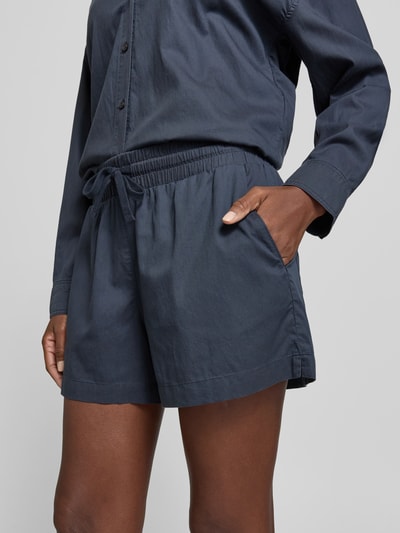 Frauenmodel trägt Shorts mit Lyocell-Anteil von Juvia in dunkelblauer Farbe mit elastischem Bund, Gesäßtaschen und Tunnelzug, Nahaufnahme Oberkörper.